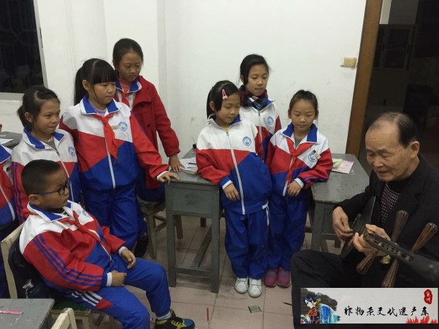 图5：丁则友（右一）为学生传授南音（2015年，晋江第五实验小学）
